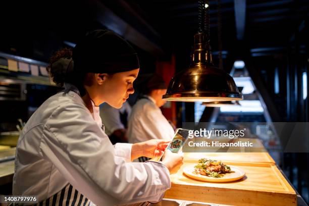 chef taking a picture of a plate at a restaurant using her cell phone - restaurant manager phone stock pictures, royalty-free photos & images