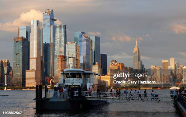 The sun sets on Hudson Yards and the Empire State Building in New York City as commuters disembark from a ferry in the Hudson River on July 14 in...