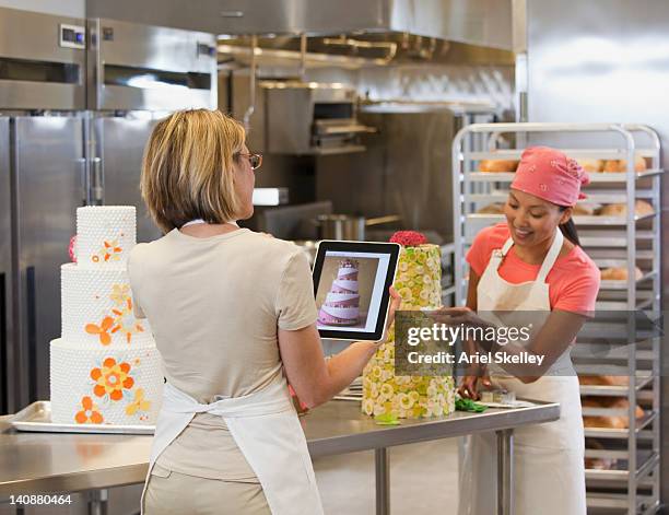 bakers using digital tablet to decorate cake in bakery - bakning business bildbanksfoton och bilder