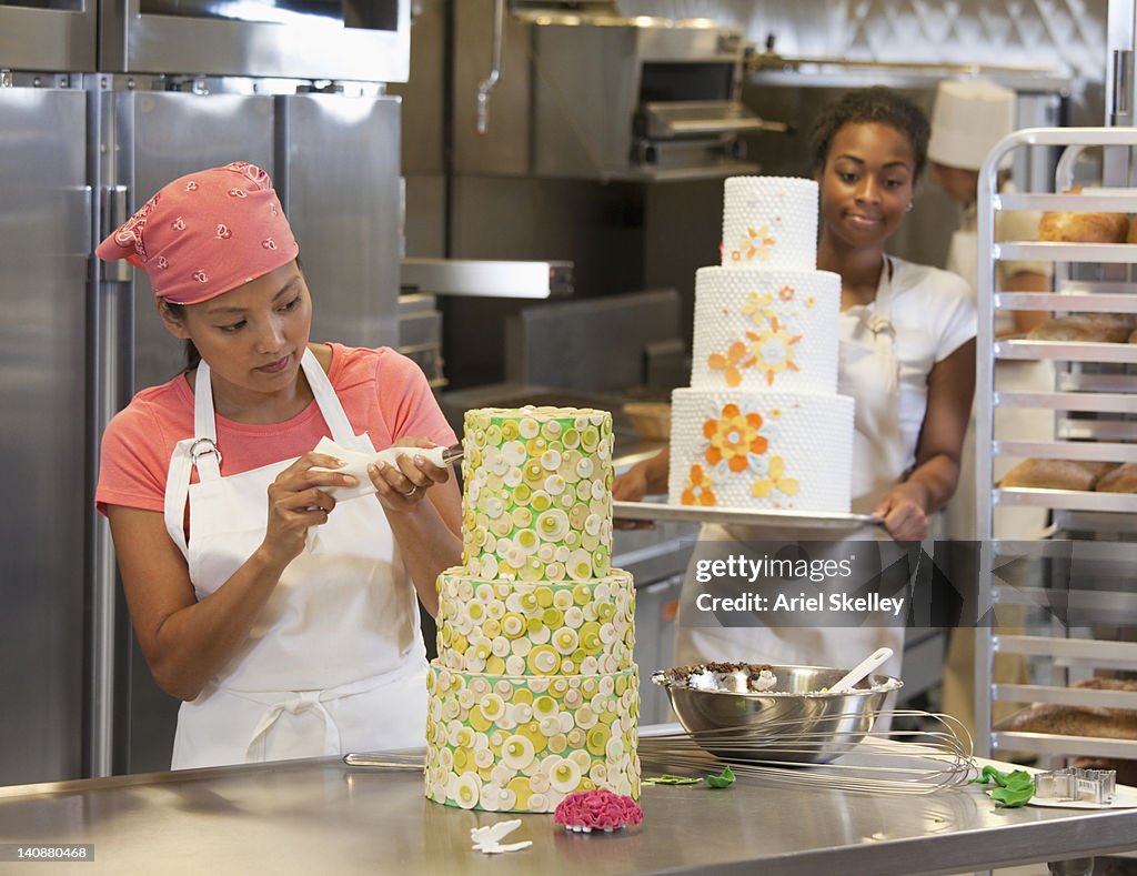 Bakers decorating elaborate cakes in bakery