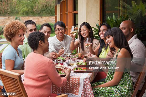 friends enjoying meal together outdoors - medium group of people stock pictures, royalty-free photos & images
