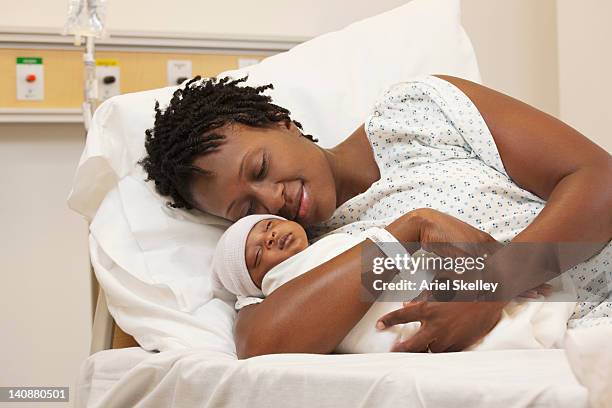 black woman holding newborn baby in hospital bed - mother newborn stock pictures, royalty-free photos & images