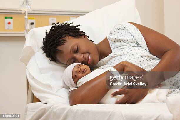 black woman holding newborn baby in hospital bed - nascimento - fotografias e filmes do acervo
