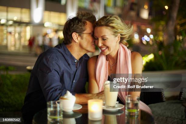 caucasian man kissing wife in restaurant - table romantique photos et images de collection