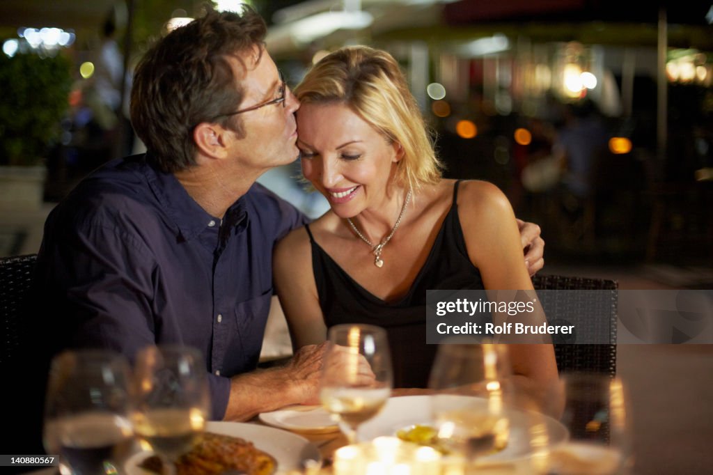 Caucasian husband kissing wife in restaurant