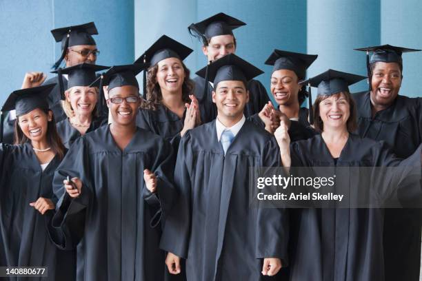 college graduates cheering in caps and gowns - graduating stock pictures, royalty-free photos & images