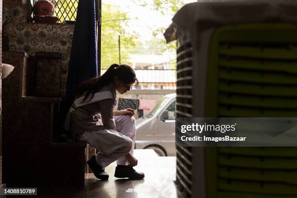 side profile of a schoolgirl trying shoe laces - school tie stock-fotos und bilder