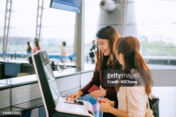 geschäftsfrauen, die den self-check-in-automaten am flughafen nutzen, um die bordkarte zu erhalten - interactive kiosk stock-fotos und bilder