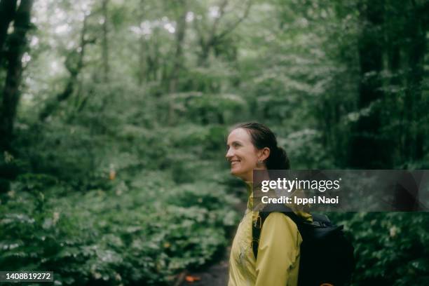 happy woman hiking in forest in rain - people rain happy stockfoto's en -beelden