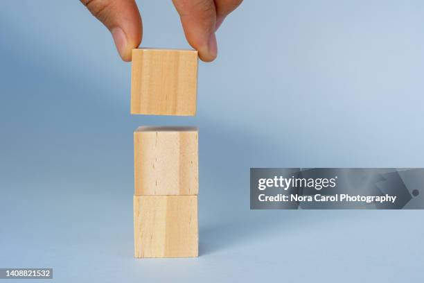 hand lifting blank wood blocks on blue background - three fingers stock pictures, royalty-free photos & images