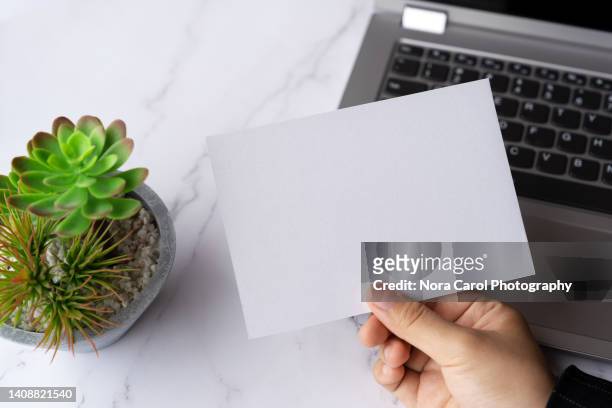 hand holding blank piece of paper - card mock up stockfoto's en -beelden
