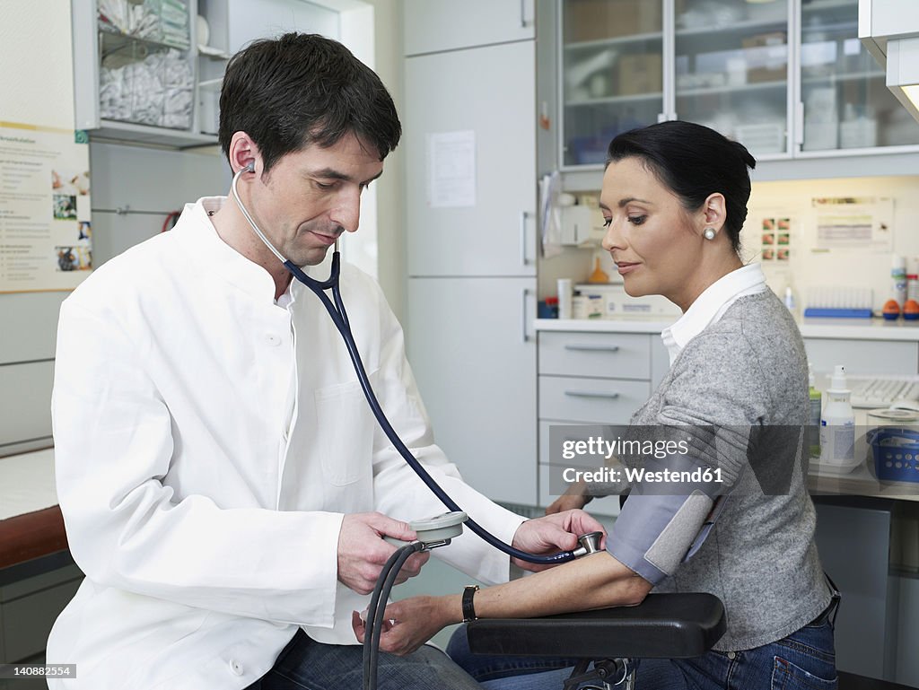 Germany, Hamburg, Doctor examining patient's blood pressure