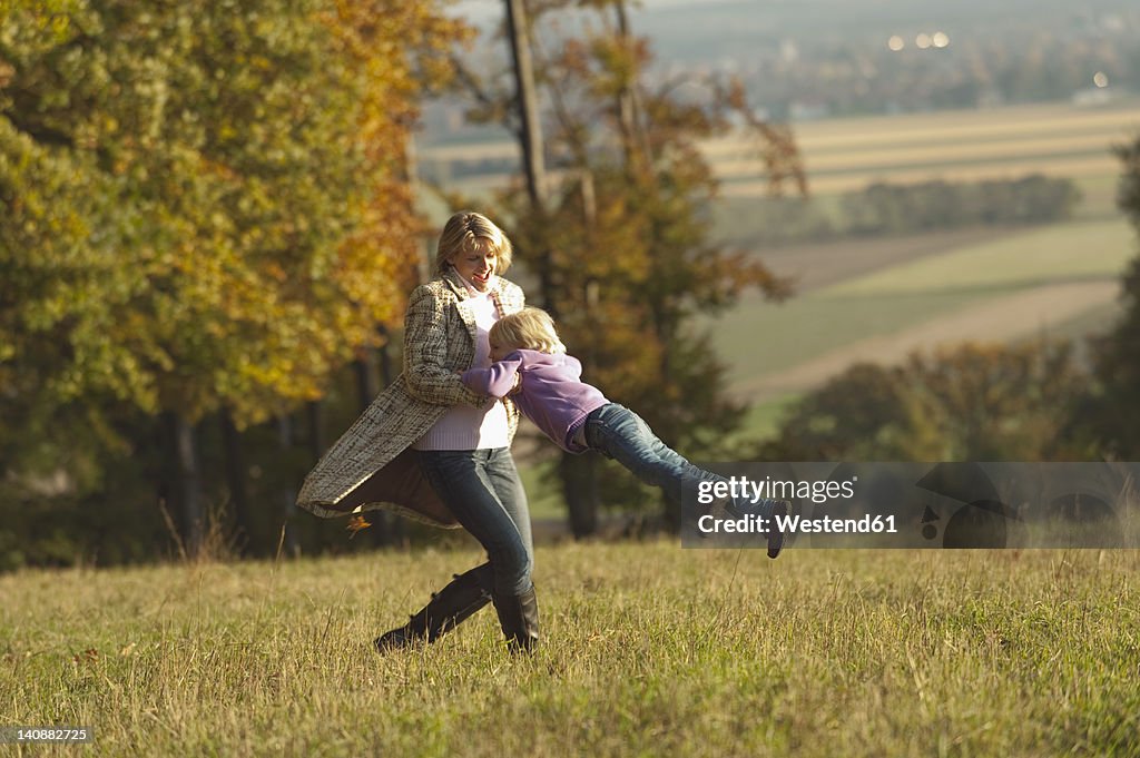 Germany, Bavaria, Mother and daughter playing in meadow during autumn