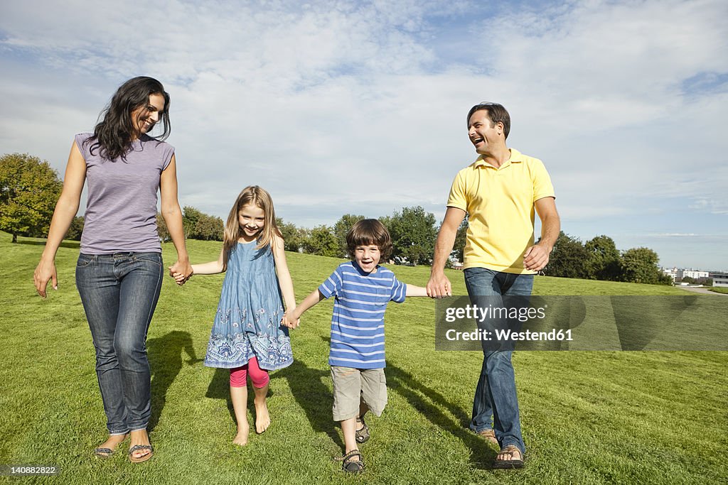 Germany, Bavaria, Family walking in grass at park