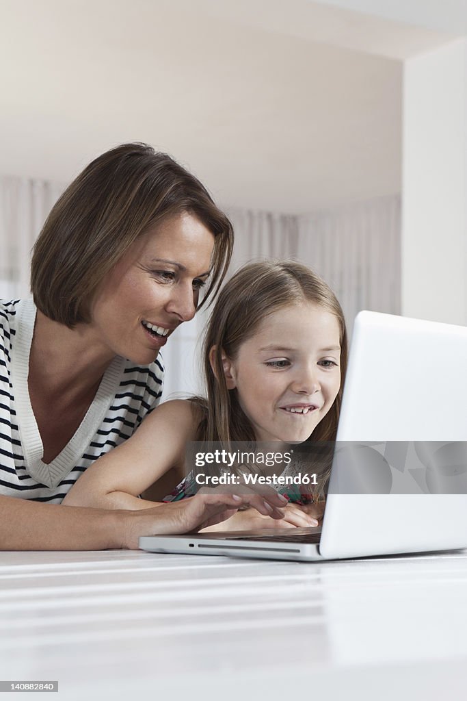 Germany, Munich, Mother and daughter using laptop, smiling