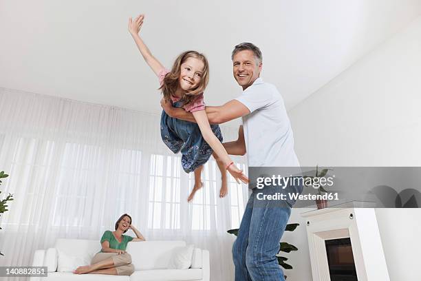 germany, munich, father playing with daughter, mother in background - pretending to be a plane stock pictures, royalty-free photos & images