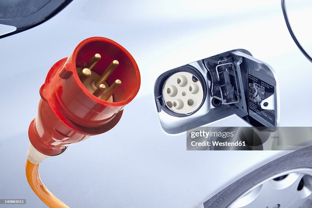 Germany, Power cord with electric car, close up