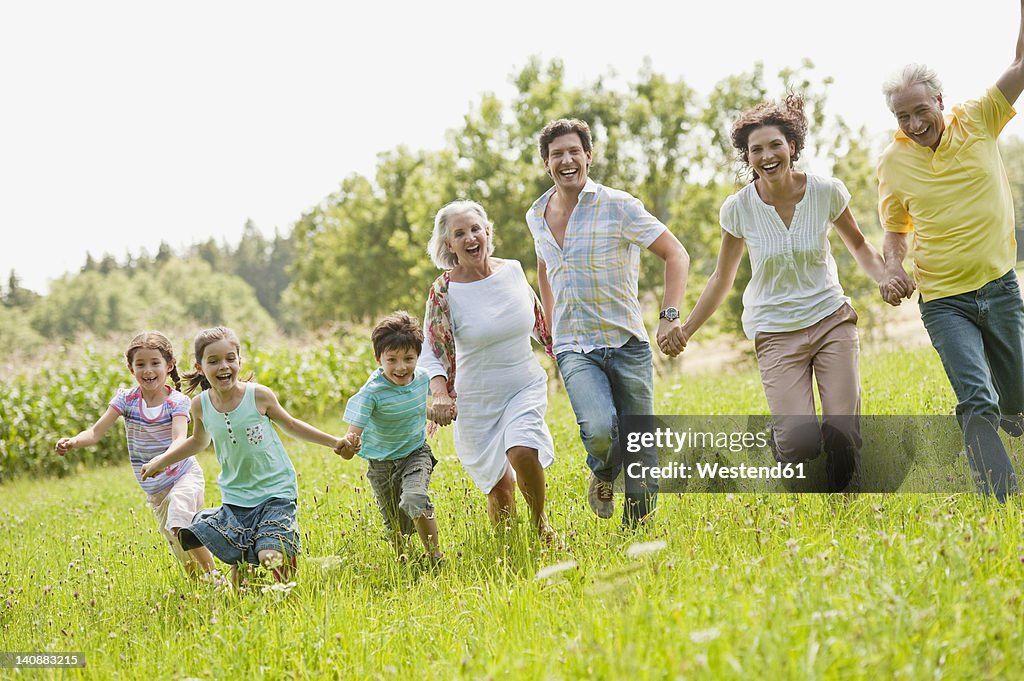 Germany, Bavaria, Family running together in grass at picnic