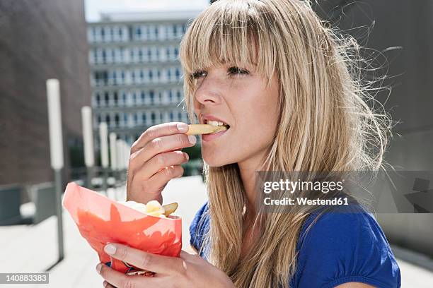 germany, cologne, young woman eating french fries - eating chips stock pictures, royalty-free photos & images