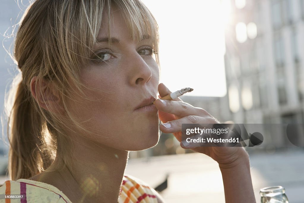 Germany, Cologne, Young woman smoking, portrait