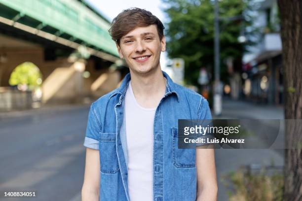 portrait of a happy young man standing on city street - un solo hombre joven fotografías e imágenes de stock