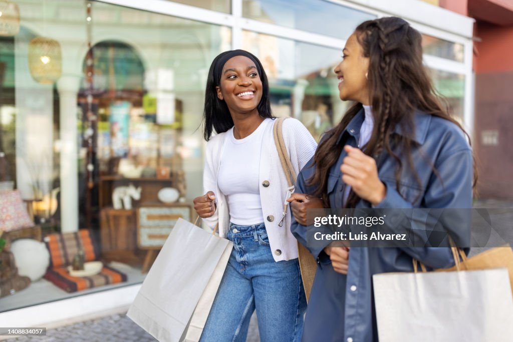 Two women friends with shopping bags walking in the city