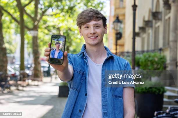 young man showing his photo on his phone - man showing phone stock pictures, royalty-free photos & images