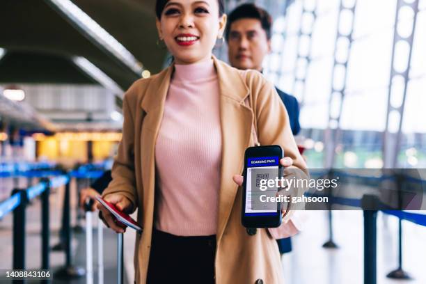 geschäftsfrau, die am sicherheitstor des flughafens mit smartphone eincheckt - kuala lumpur airport stock-fotos und bilder