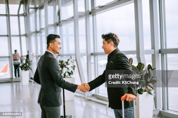 gente de negocios dándose la mano en el aeropuerto - expatriado fotografías e imágenes de stock