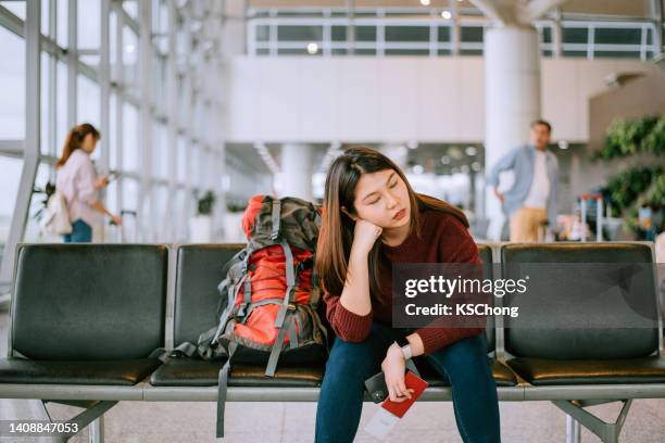 mujer aburrida con mochila en la sala de espera del aeropuerto - cancelación fotografías e imágenes de stock