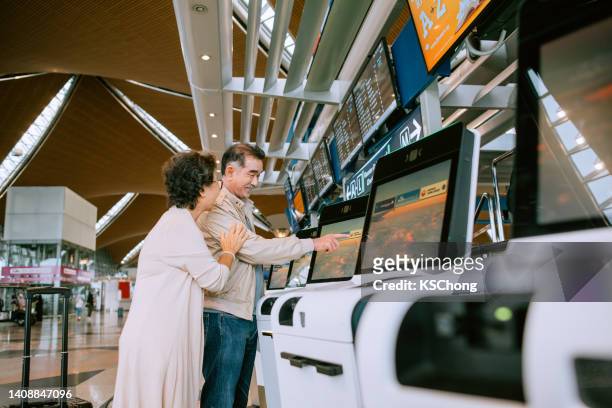 husband & wife are using kiosk to check in at airport - state of emergency sign stock pictures, royalty-free photos & images