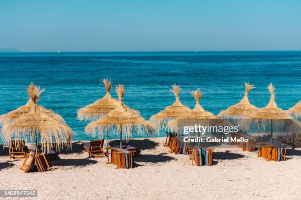 beach umbrella made of straw and sea view - albania fotografías e imágenes de stock