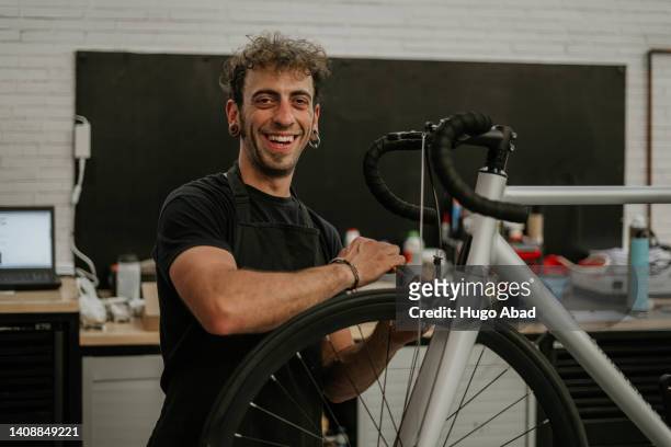 mechanic repairing bicycle and looking at camera. - fahrrad reparieren stock-fotos und bilder