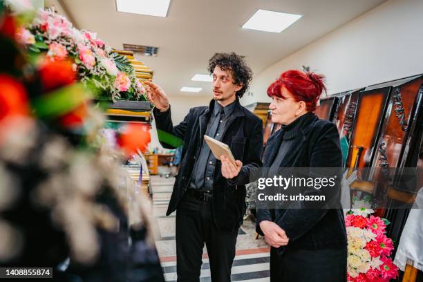 undertaker showing coffins to a widow - begrafenisondernemer stockfoto's en -beelden