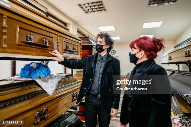 undertaker showing coffins to a widow - funeral parlor stockfoto's en -beelden