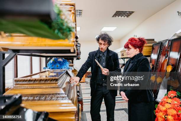 undertaker showing coffins to a widow - funeral parlor stockfoto's en -beelden