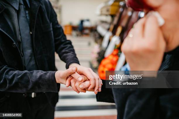 son comforting his mother in funeral parlor - rouwstoet stockfoto's en -beelden