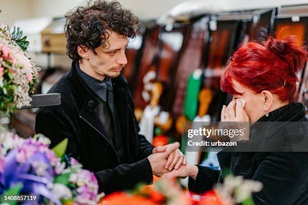 son comforting his mother in funeral parlor - widow stock pictures, royalty-free photos & images