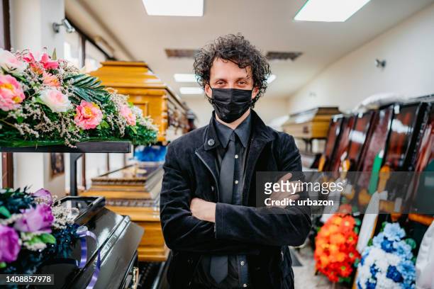 undertaker in funeral parlor with face mask - funeral merchandise stock pictures, royalty-free photos & images