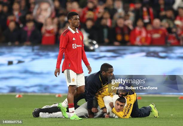 Pitch invader is tackled by security during the Pre-Season friendly match between Melbourne Victory and Manchester United at Melbourne Cricket Ground...