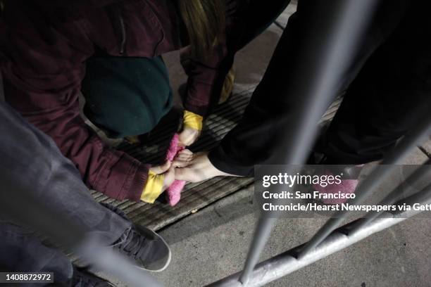 Rochelle Rodas, left, puts one of her socks on her mom's foot as they wait for Black Friday to begin. Collette had left the house in sandals and...