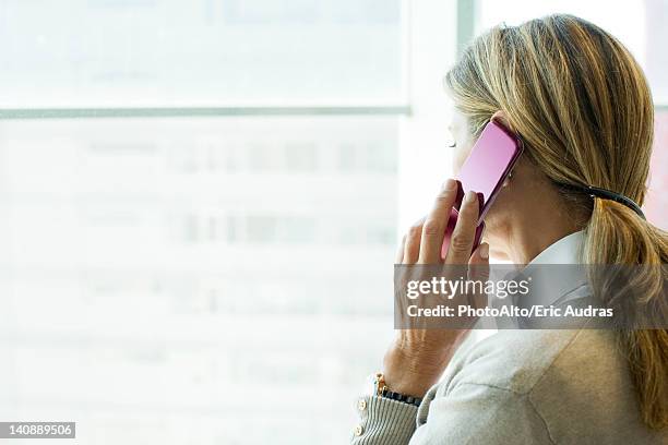 woman using cell phone, looking out window - private view stockfoto's en -beelden