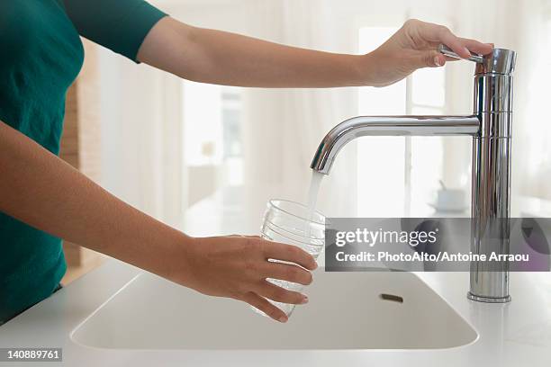 woman filling glass of water at kitchen sink, cropped - kitchen sink running water stock pictures, royalty-free photos & images