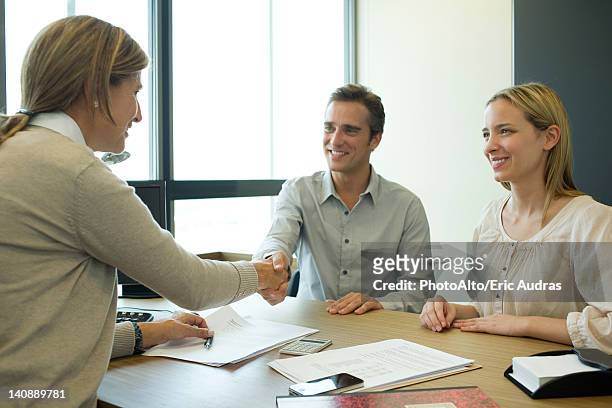couple shaking hands with businesswoman in office - couple at bank fotografías e imágenes de stock