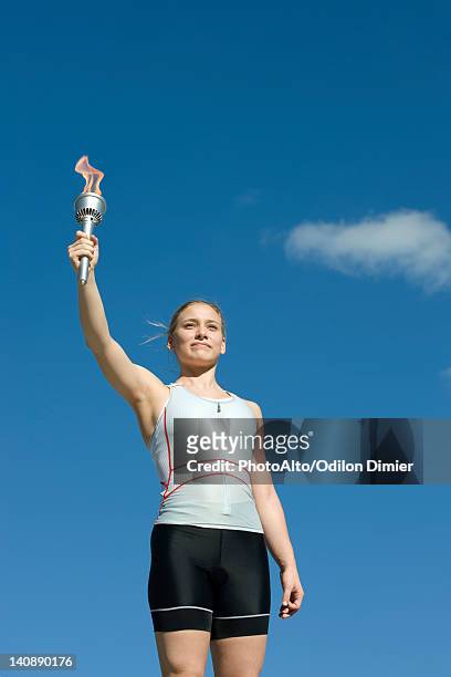 female athlete holding up torch - olympische spiele stock-fotos und bilder