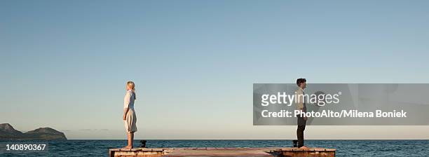 couple standing back to back on pier, side view - ignore stock-fotos und bilder
