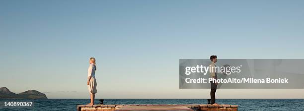 couple standing back to back on pier, side view - middlebare afstand stockfoto's en -beelden