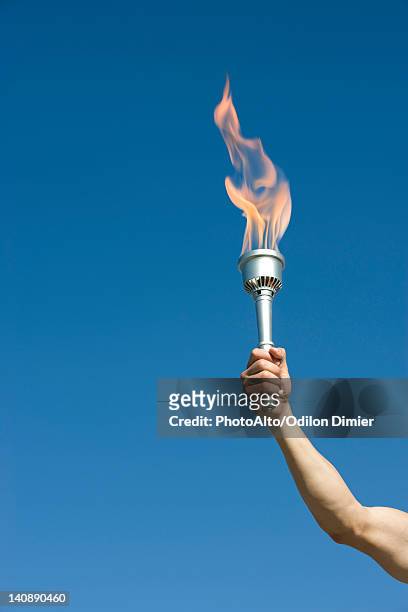man's arm holding up torch - giochi olimpici foto e immagini stock