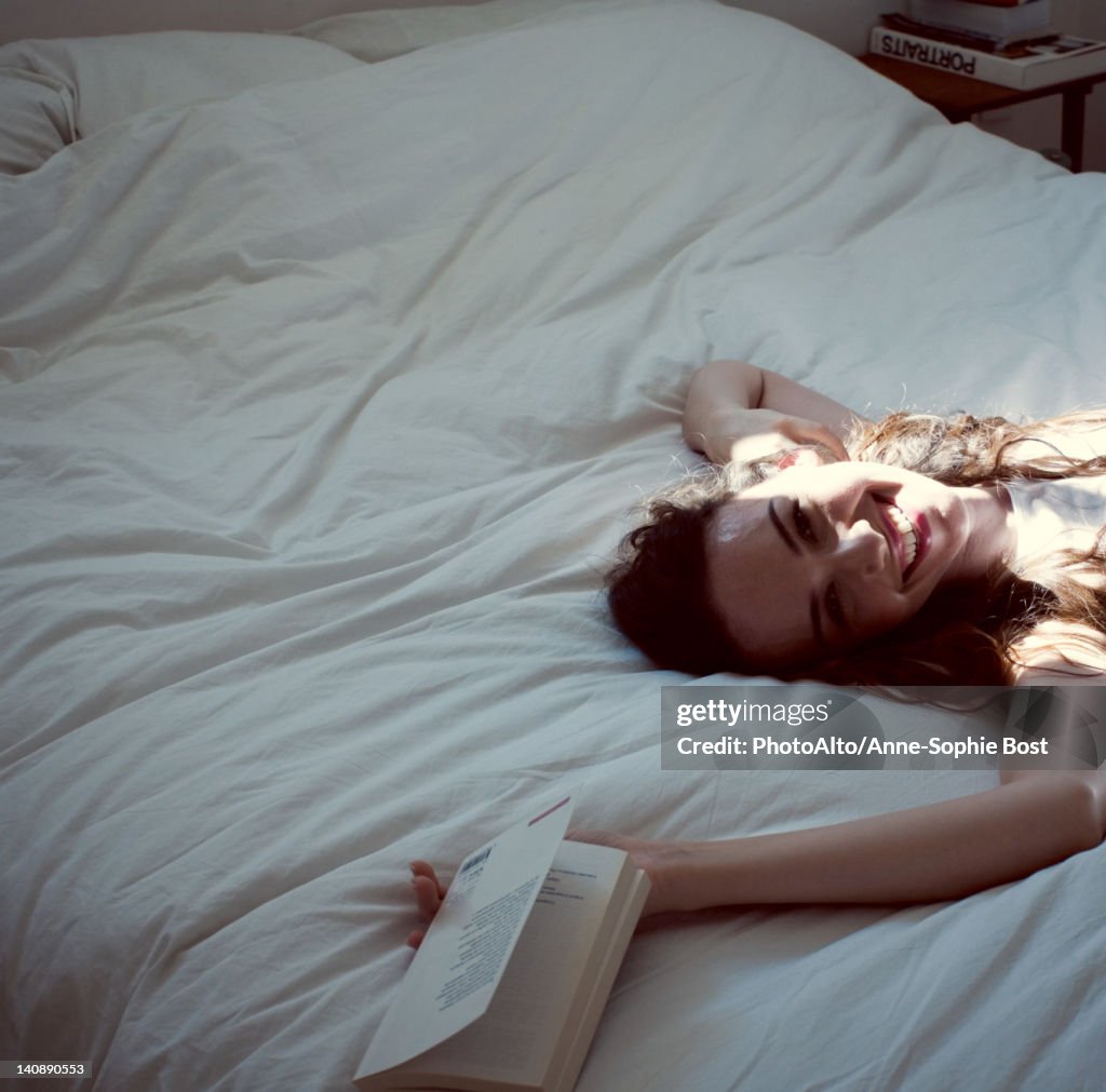 Mid-adult woman relaxing on bed, cropped