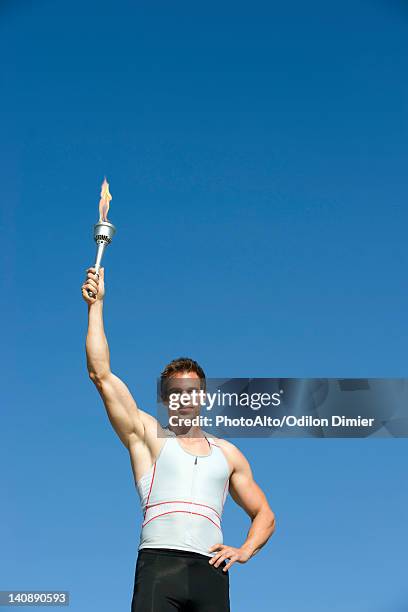 male athlete holding up torch - jeux olympiques photos et images de collection